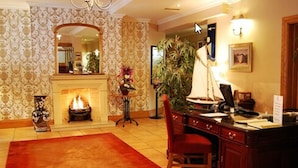 A room with a fireplace, a desk, a chair, and a large plant. - WatersEdge Hotel (Cobh)