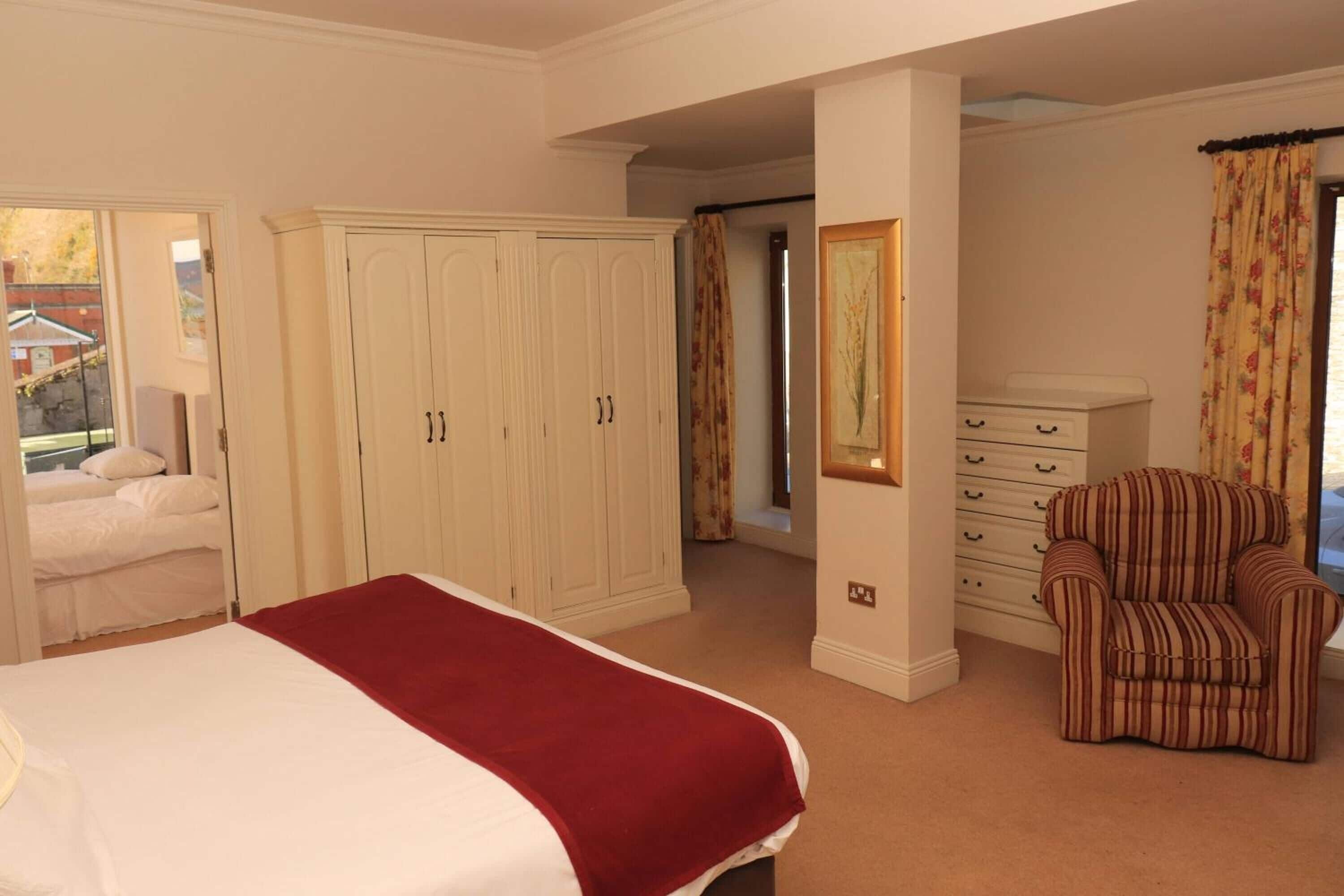 A bedroom with a bed, a wardrobe, a chair, and a dresser.