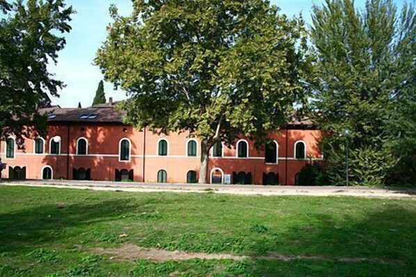 A red brick building with arched windows and a large tree in front.