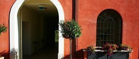 A building with a red facade, an arched entrance, and a window with a grid pattern.