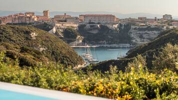 Vista costera con piscina, barcos y edificios en una colina.