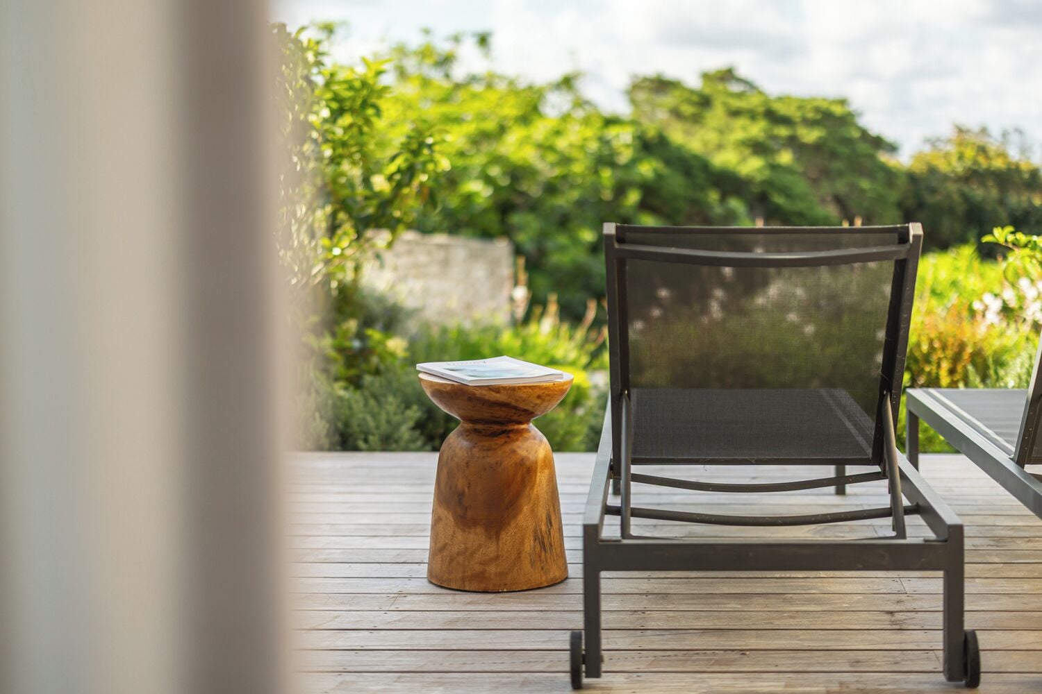 A wooden deck with a metal chair and a wooden stool.