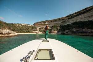 Un barco con una persona de pie en la proa, una vista despejada del paisaje circundante y aguas tranquilas.
