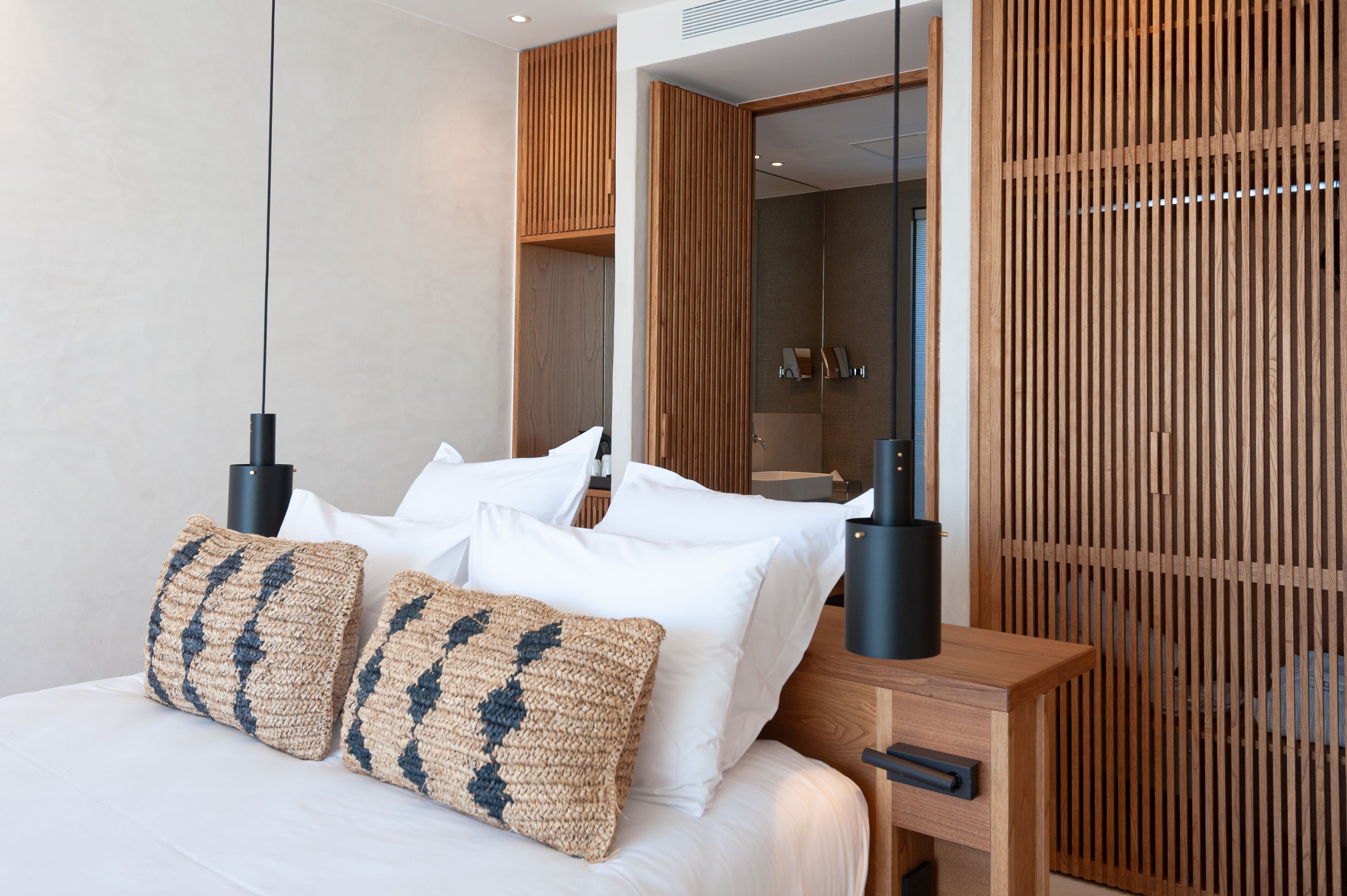 A modern bedroom with a wooden headboard, a bedside table, and a large mirror.