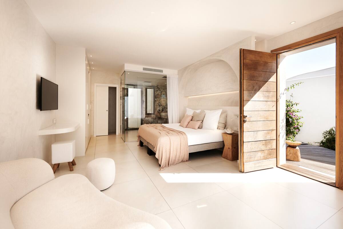 A modern bedroom with a bed, bedside table, and a TV mounted on the wall.