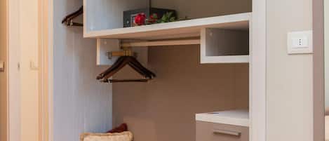 Ein moderner, gut beleuchteter begehbarer Kleiderschrank mit eingebauten Regalen, einer Kleiderstange und einer Sitzbank mit Staufächern.