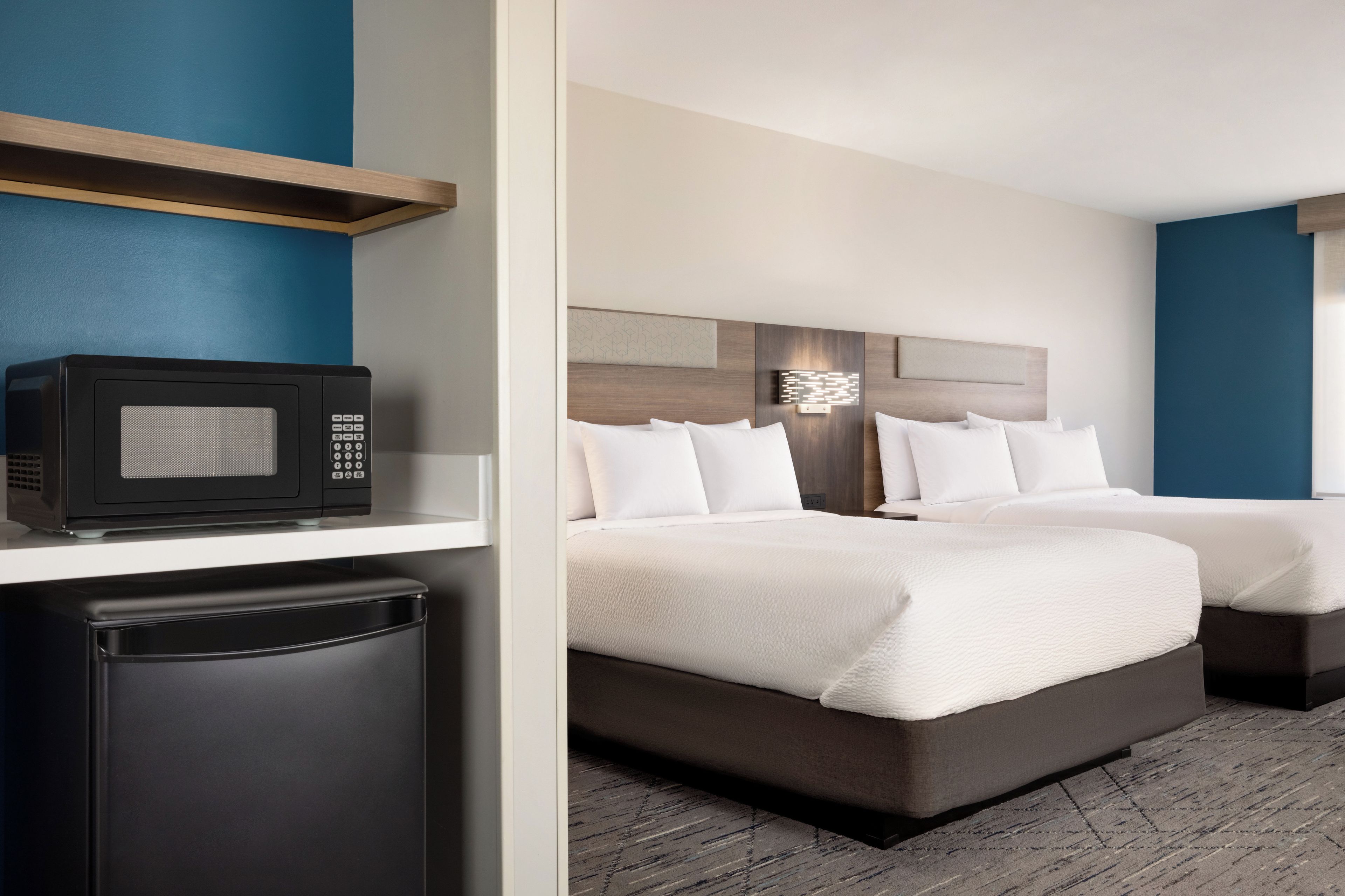 Una habitación de hotel con cama, mesitas de noche, microondas y refrigerador.