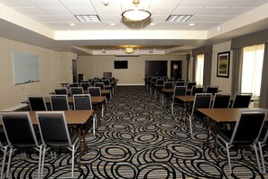 Un salón de conferencias con alfombra estampada, varias mesas y sillas dispuestas para reuniones.