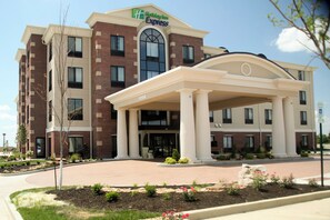 A Holiday Inn Express building with a brick facade, a central entrance with a covered walkway, and a landscaped front yard.
