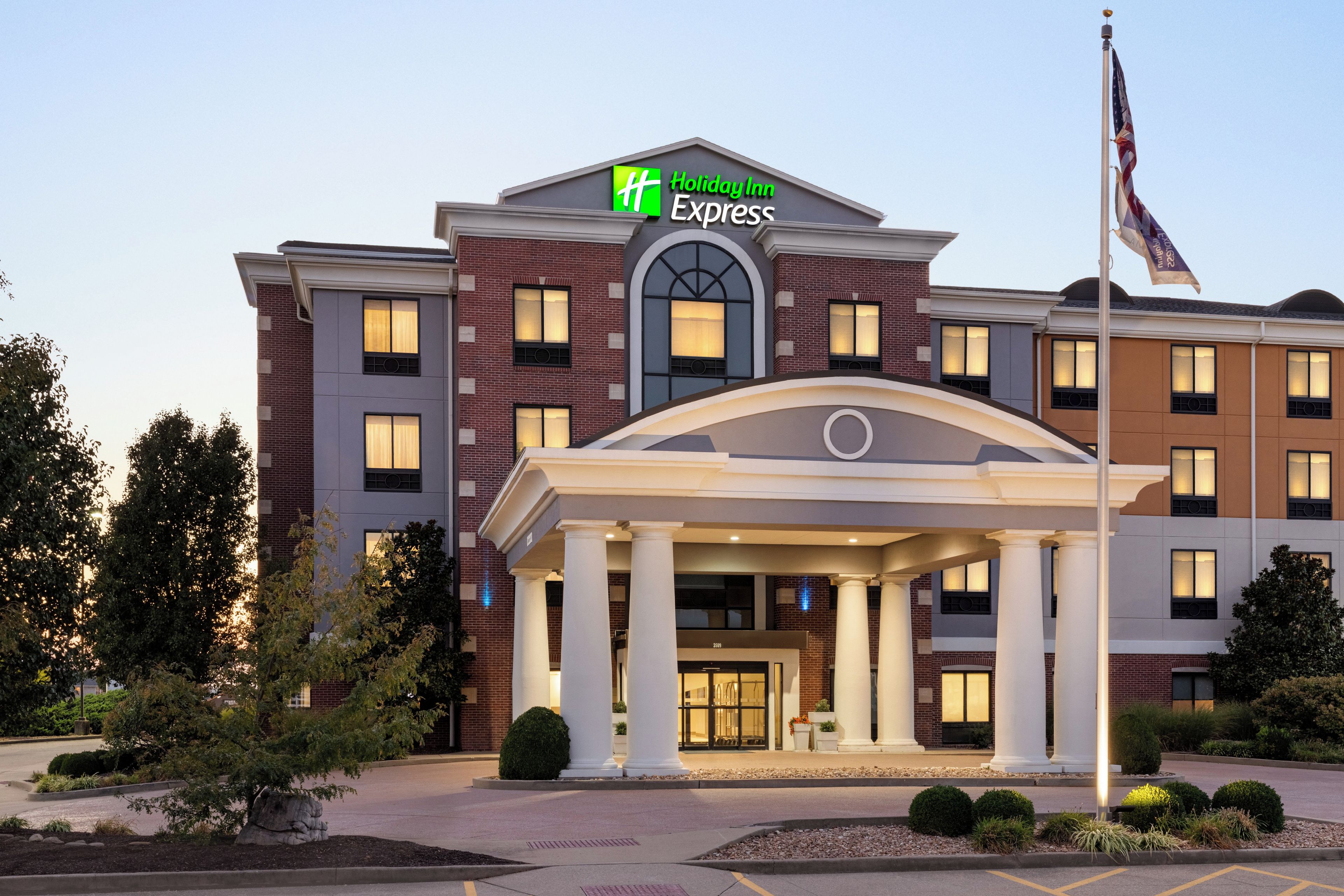 Un hotel Holiday Inn Express con fachada de ladrillo, amplias ventanas y una entrada central con columnas.