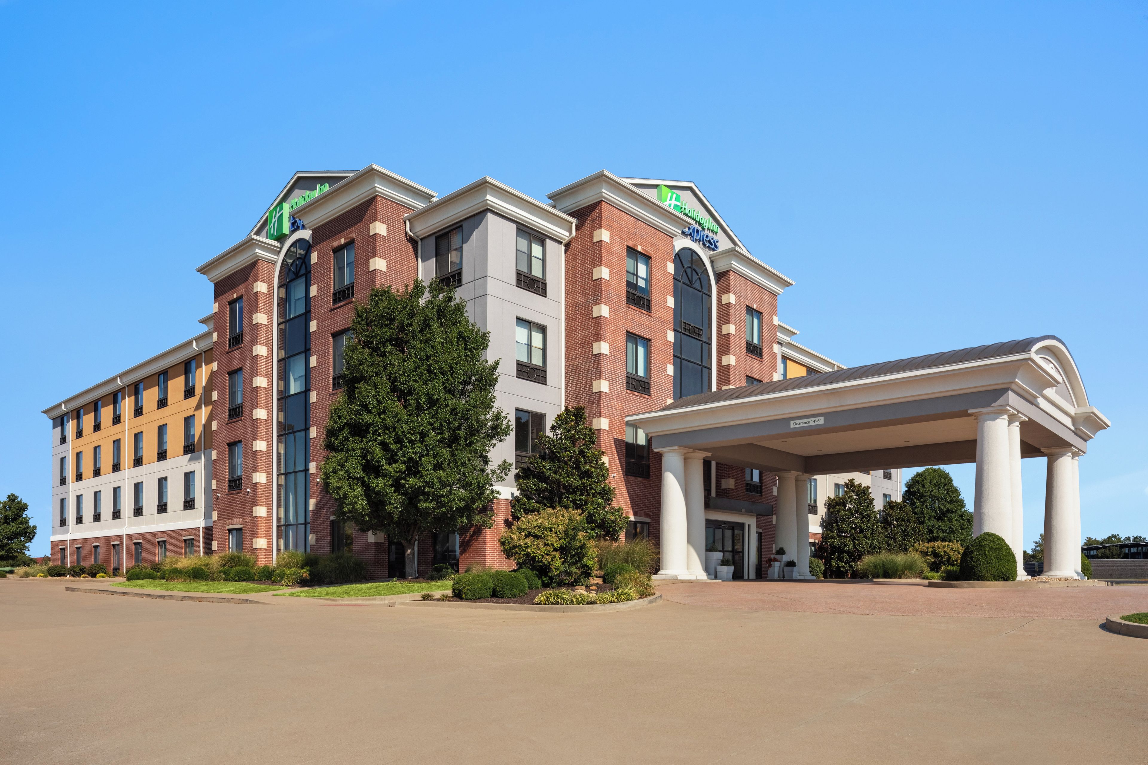A multi-story hotel with a central entrance and a covered parking area.