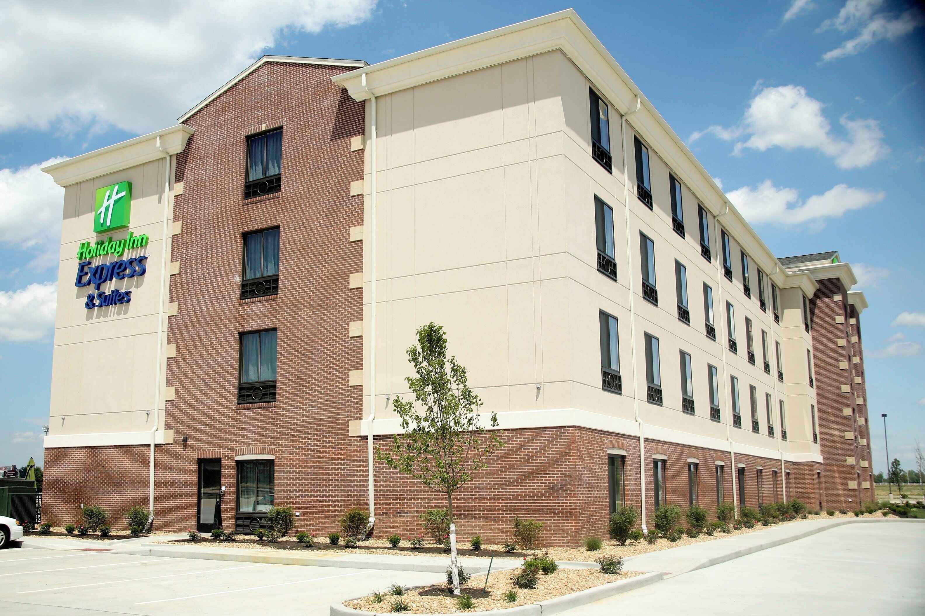 Un hôtel Holiday Inn Express & Suites avec une façade en briques, de nombreuses fenêtres et un parking.