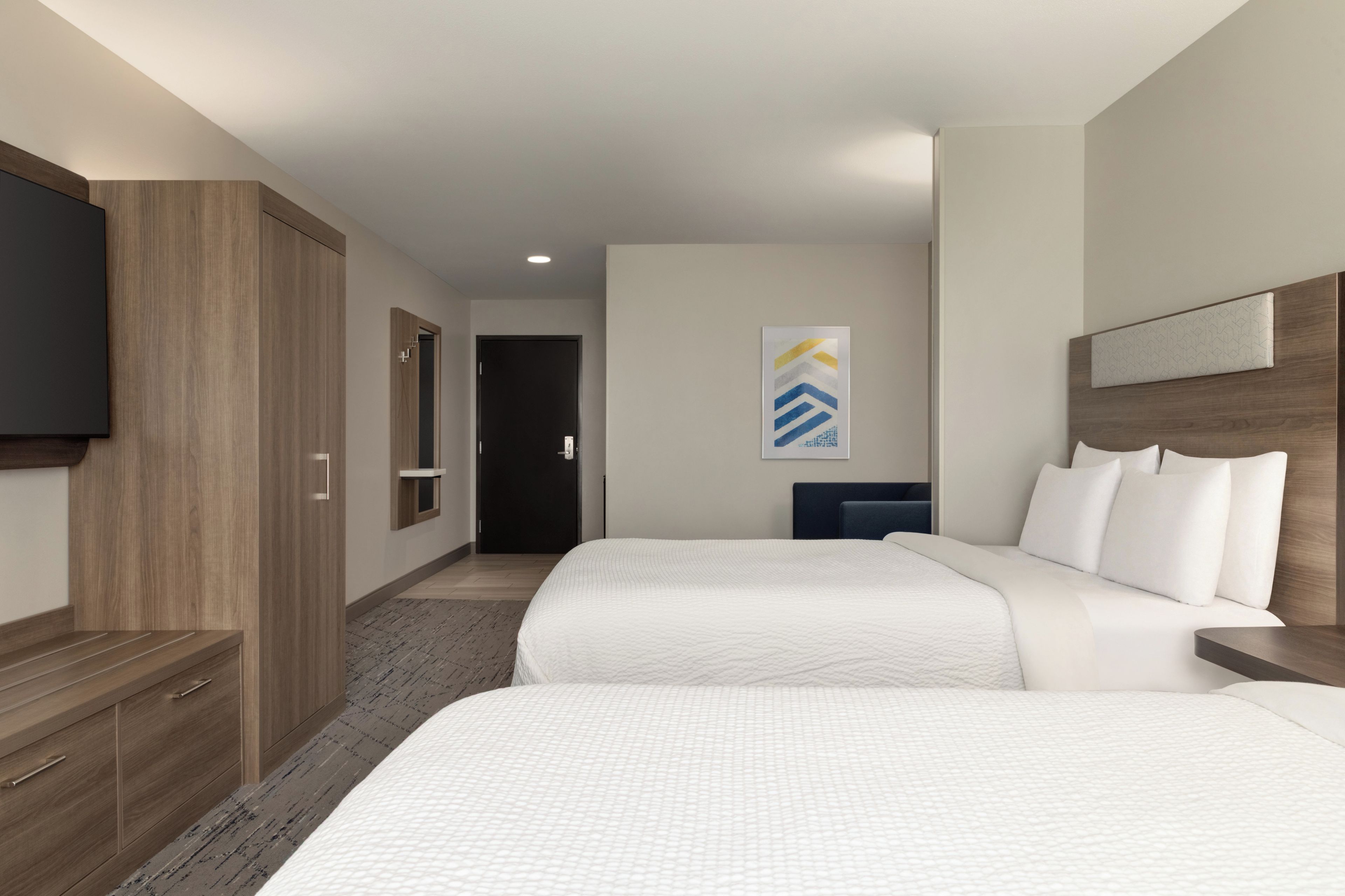 A hotel room with two beds, a flat-screen TV, a wooden wardrobe, and a painting on the wall.