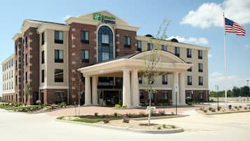 A Holiday Inn Express hotel with a brick facade, a central entrance with a covered walkway, and an American flag.
