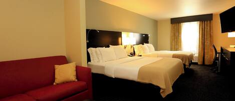 A hotel room with two beds, a red sofa, a desk, and a TV.