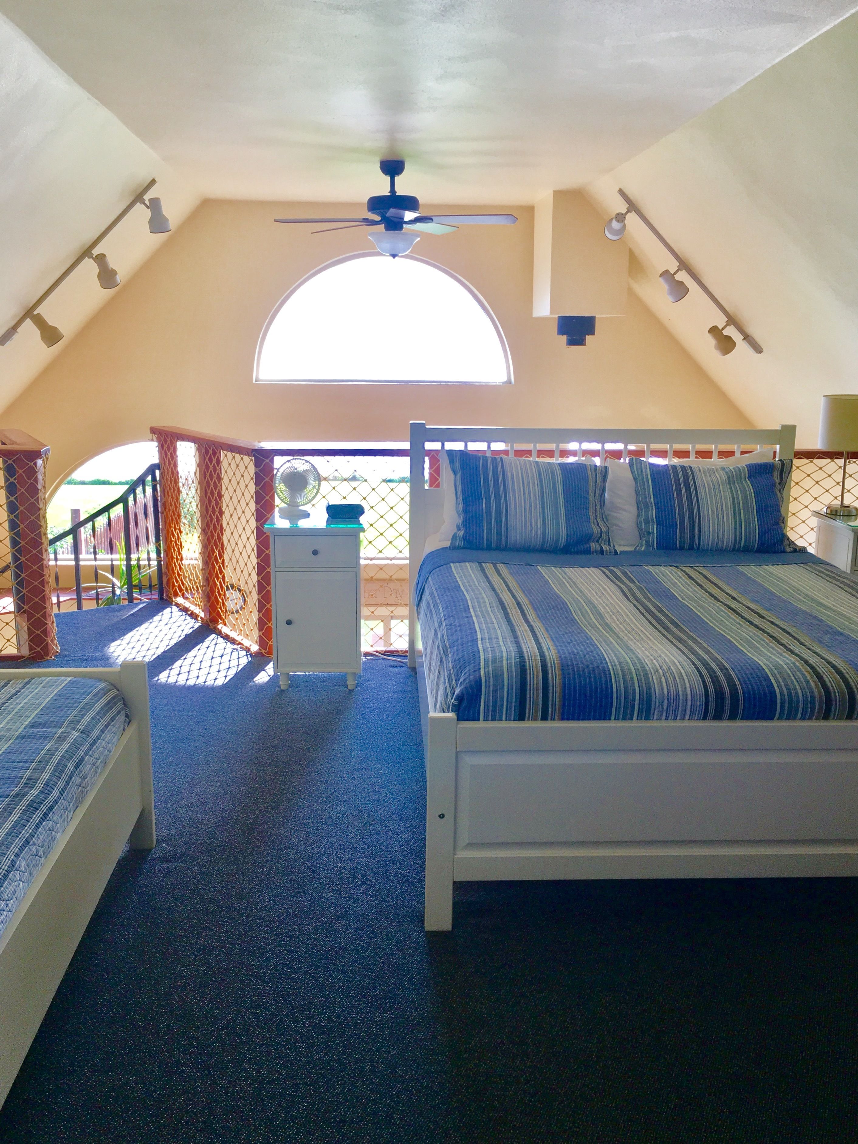 A bedroom with a large bed, a ceiling fan, and a window.