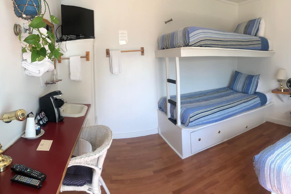 Une chambre avec des lits superposés, un bureau avec une lampe, une chaise et une table de chevet avec une lampe.