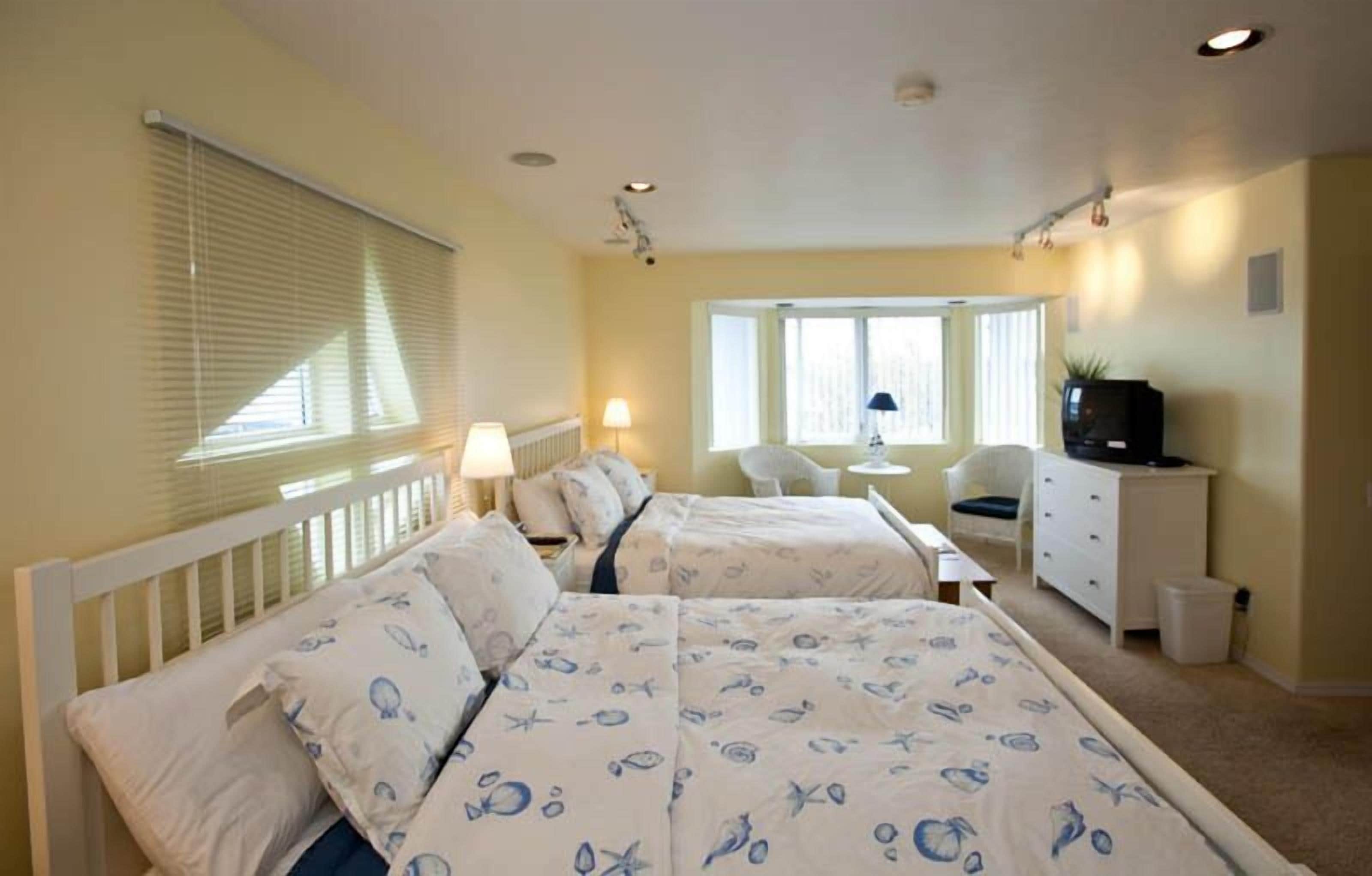 Une chambre avec deux lits, un bureau, une chaise et un téléviseur.