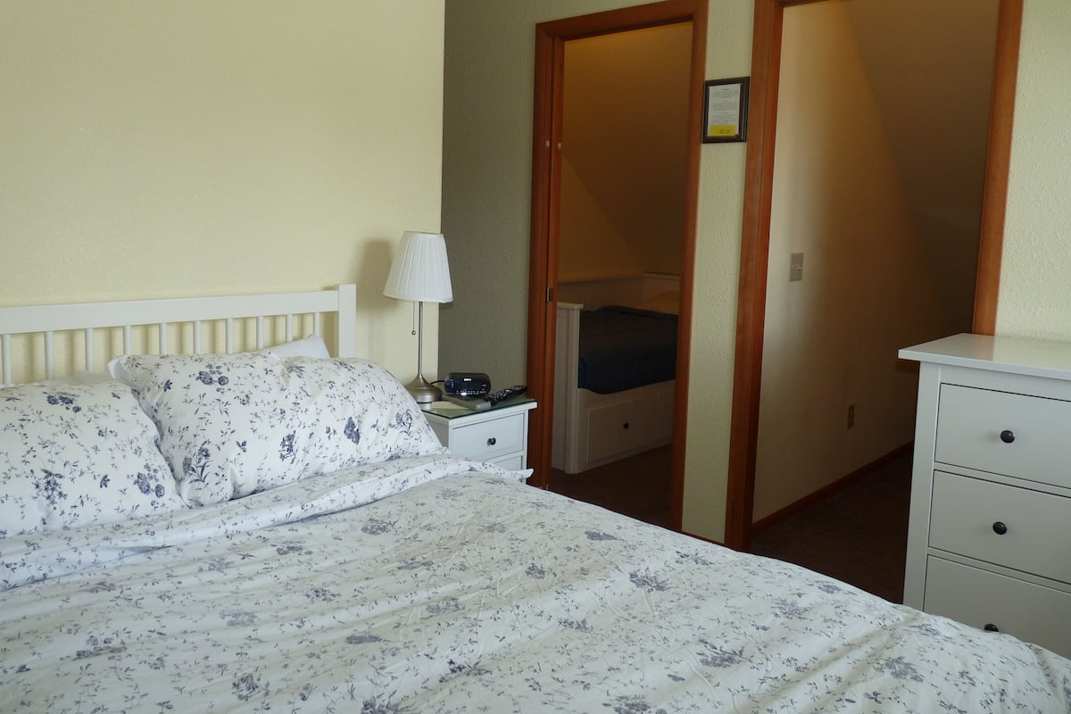 Une chambre à coucher avec un lit, des tables de chevet, une lampe et une armoire.