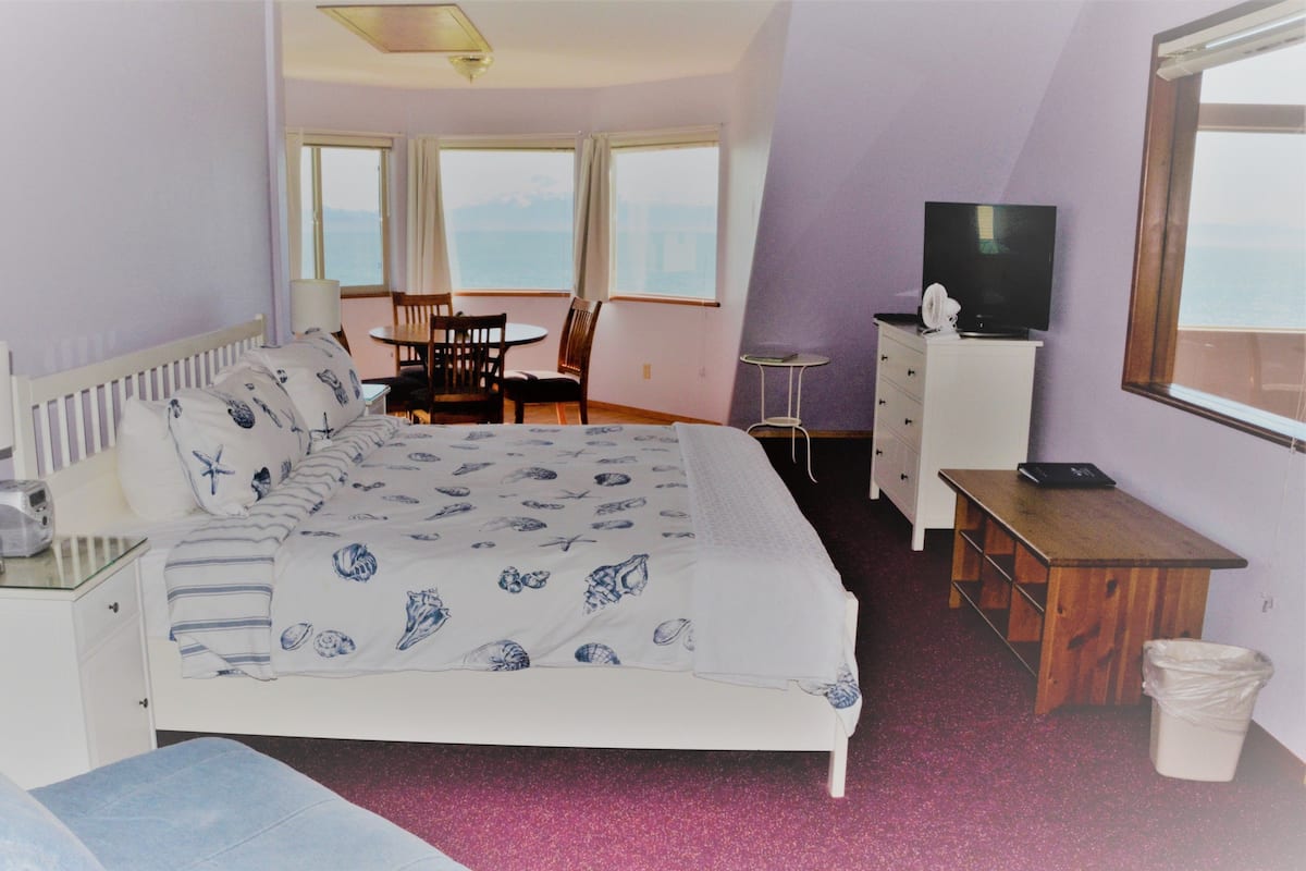 Une chambre avec un lit, un bureau, une chaise, une télévision et une fenêtre donnant sur un beau paysage.