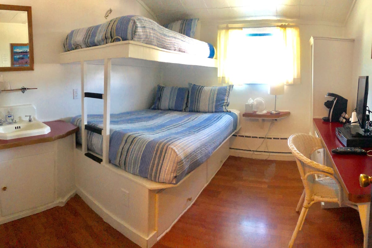 Une chambre avec un lit superposé, un lavabo, une chaise et un bureau avec un ordinateur.