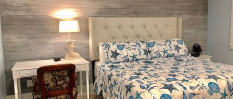 A bedroom with a bed, a desk, and a chair.
