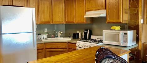 Una cocina con armarios de madera, un refrigerador, una estufa, un microondas y un lavaplatos.