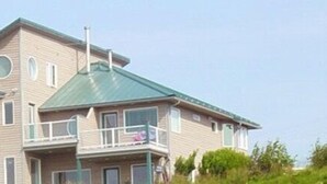 A multi-story house with a green roof, a balcony, and a chimney. - Driftwood Inn and Seaside Lodges (Homer)