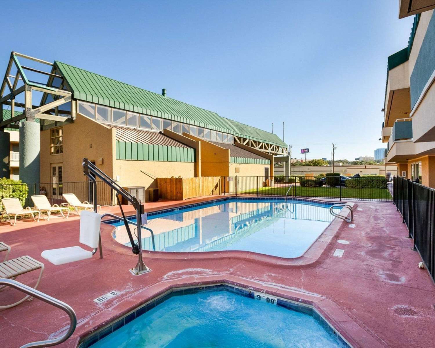 A rooftop swimming pool with lounge chairs and a covered area with a green roof.