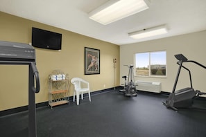 A gym with exercise equipment, a TV, a window, and a chair. - Baymont by Wyndham Evansville North/Haubstadt (Haubstadt)