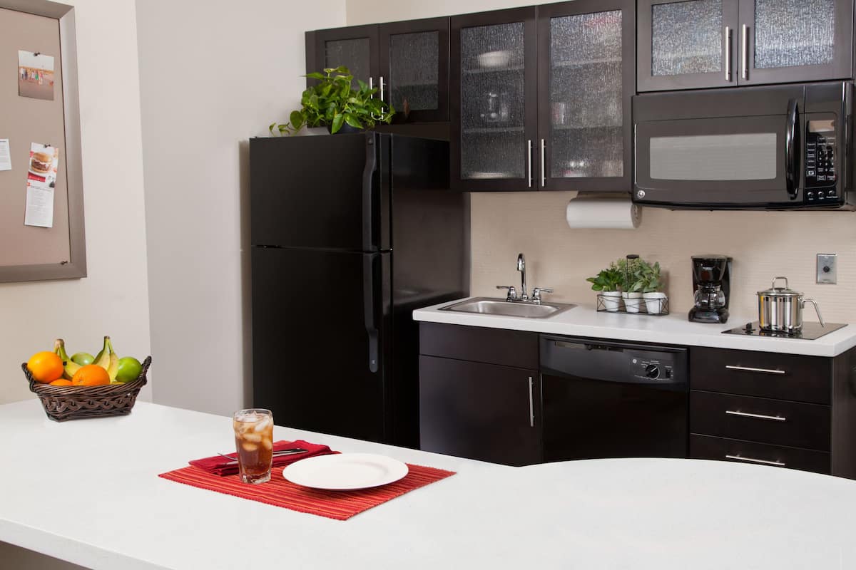 A modern kitchen with a black refrigerator, a microwave, a sink, and a coffee maker.