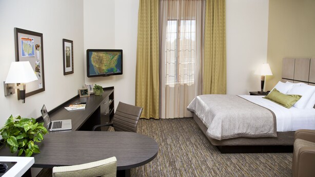 Een hotelkamer met een bed, bureau, stoel, lamp en een kaart aan de muur.