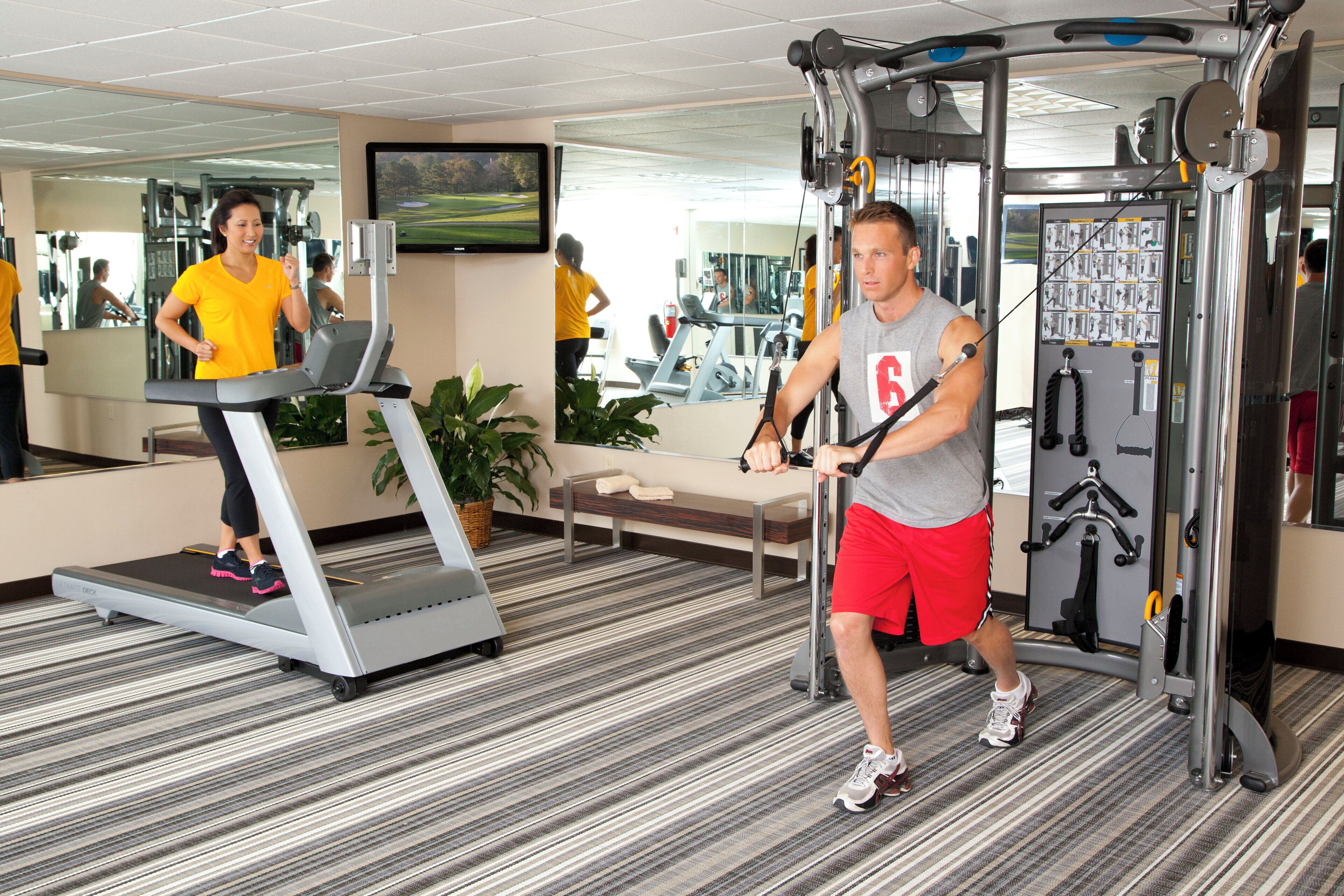 A gym with treadmills, a weight machine, and a mirror reflecting the interior.