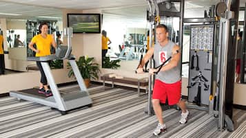 A gym with treadmills, a weight machine, and a mirror reflecting the interior.
