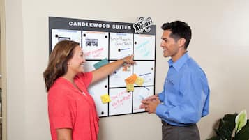 Un tablón de anuncios con varios mensajes e información, incluyendo una sección titulada 'CANDLEWOOD SUITES' y otra llamada 'PRÓXIMOS EVENTOS'.