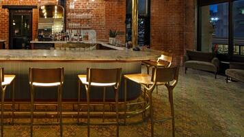 A bar area with a marble countertop, bar stools, and a large mirror.