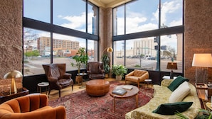 A spacious lobby with large windows, leather armchairs, a patterned rug, and a variety of seating options.
