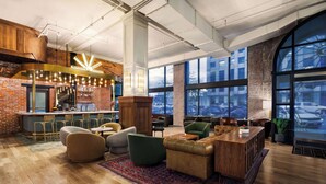 A modern lounge area with a bar, seating, and large windows offering views of parked cars.