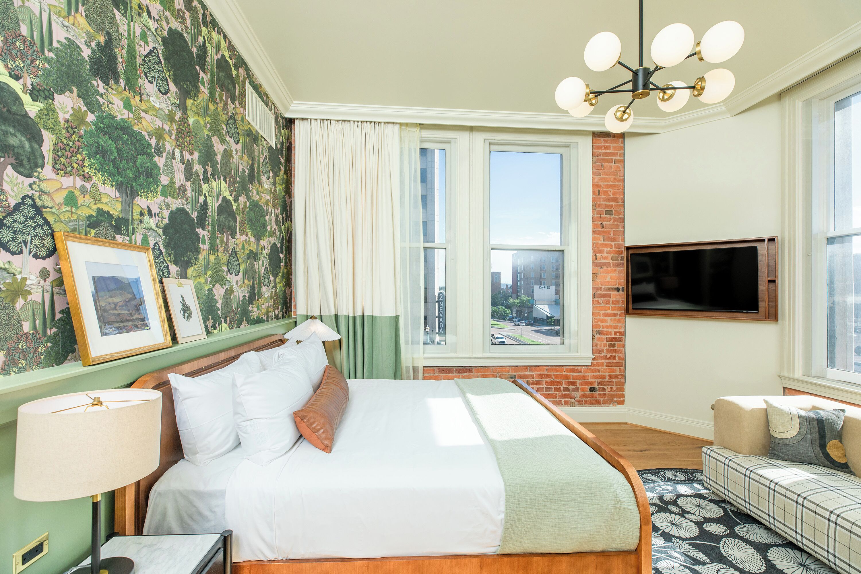 Une chambre d’hôtel avec un grand lit, une télévision, un canapé et une fenêtre donnant sur la ville.
