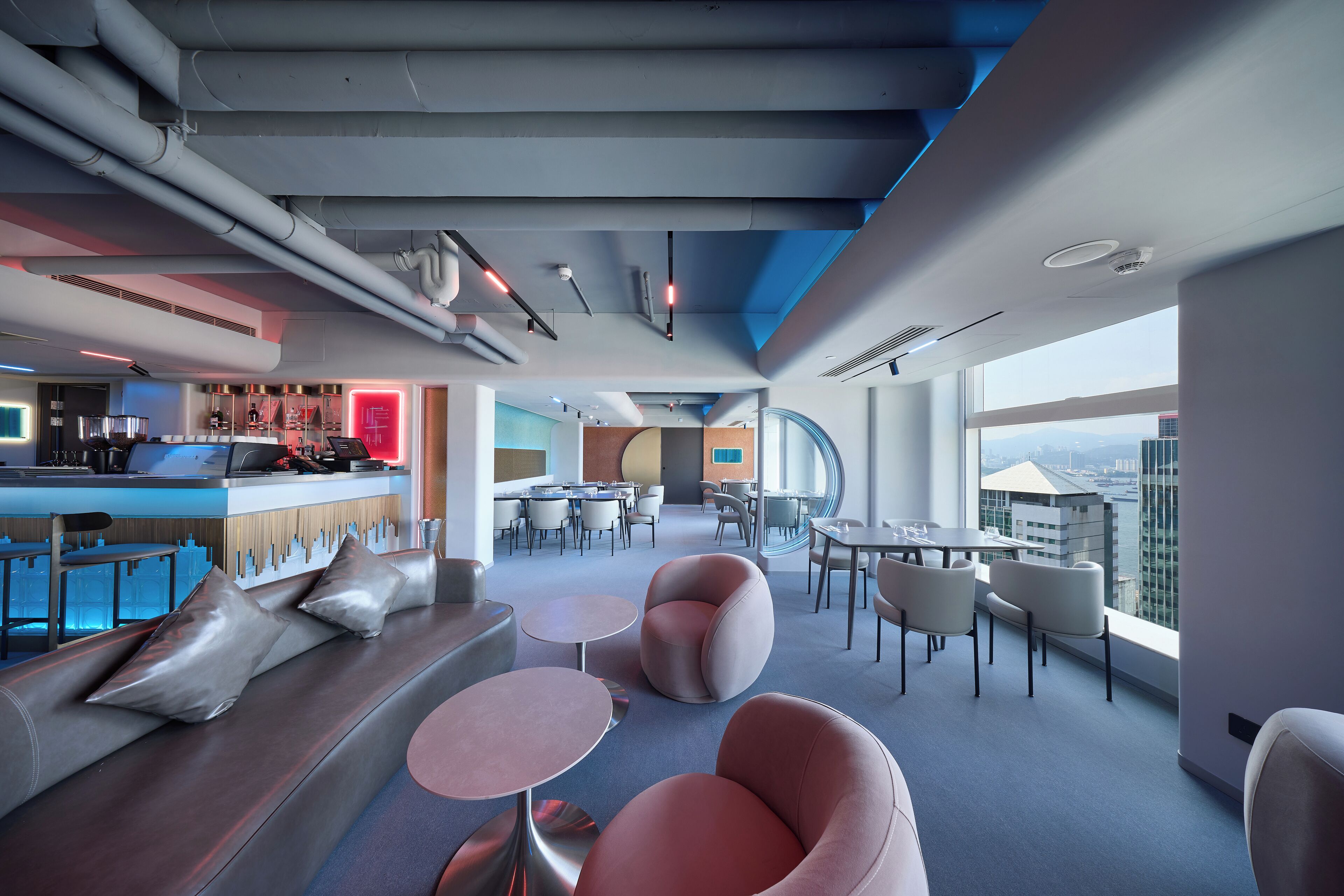 A modern lounge area with seating, tables, and a bar.