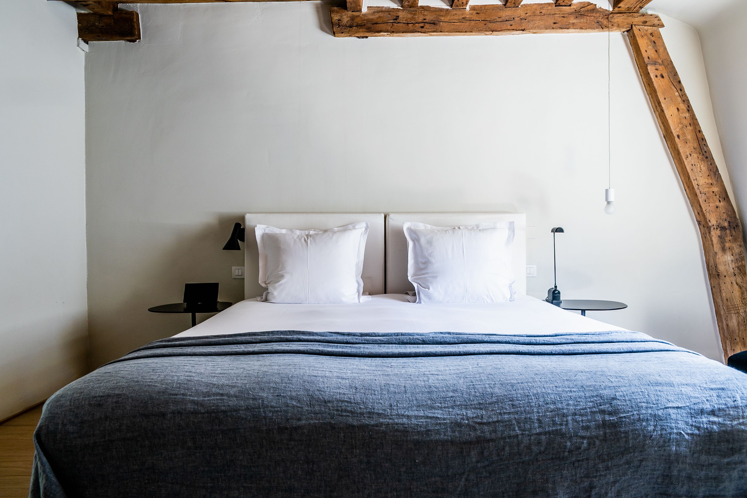 A bedroom with a bed, two bedside tables, and a wooden beam structure above the bed.