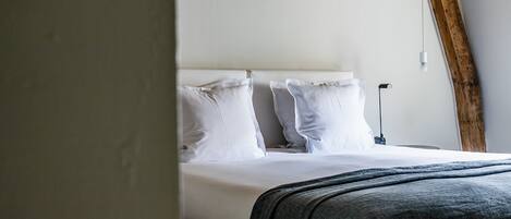 A neatly made bed with white linens and a dark gray throw blanket.