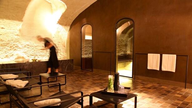 A spa room with massage tables, a large mirror, and a stone wall. - Hotel Julien (Antwerp)