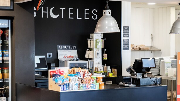 A hotel reception area with a black counter, a computer, and a sign that reads "HOTELES". - As Hotels Chucena (Chucena)