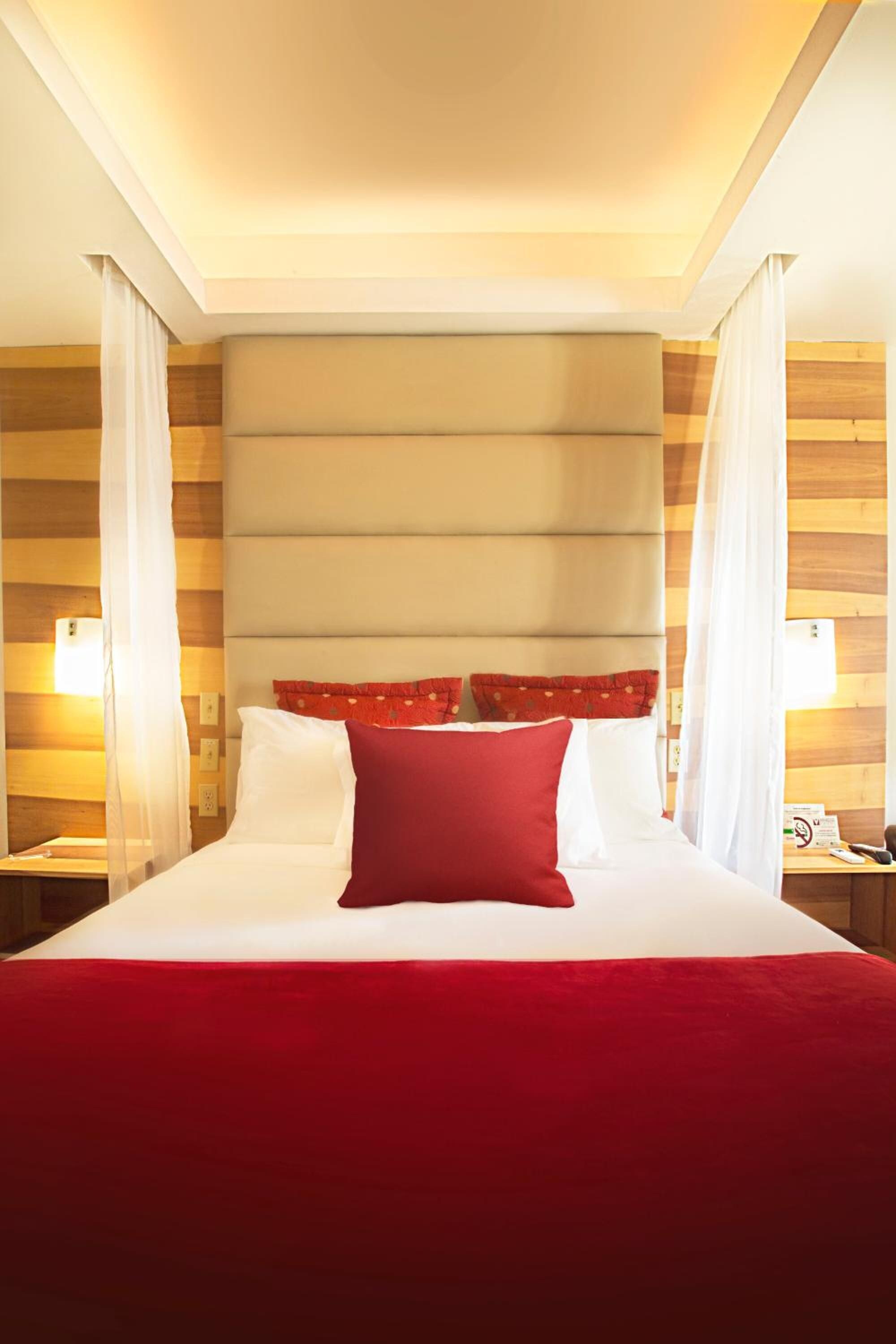 Una habitación de hotel con una cama grande, un cabecero de madera y dos lámparas de noche.