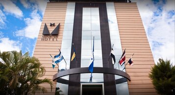 Exterior del Hotel Minister, con un diseño moderno, que presenta una entrada destacada y varias banderas.