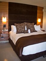 Habitación de hotel con una cama grande, dos mesitas de noche y un teléfono montado en la pared.