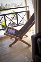 Un balcón con una silla de madera y vistas a la ciudad.