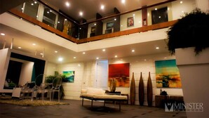 Un vaste espace intérieur doté d’un haut plafond, d’un coin salon avec un canapé et des fauteuils, et d’œuvres d’art accrochées aux murs.