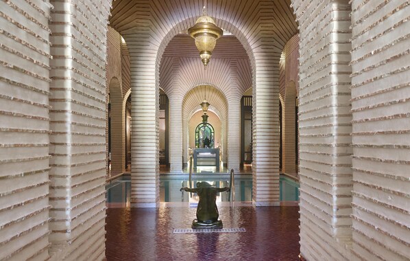 A corridor with arches and a central fountain.